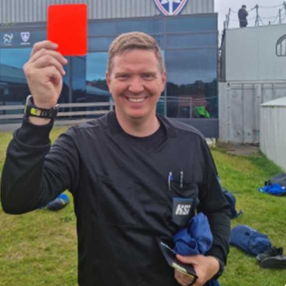 A smiling referee holding up a red card